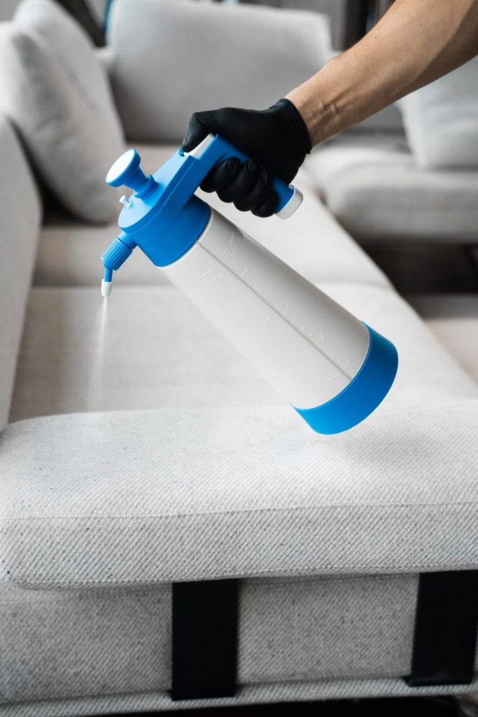 Spraying cleaning solution on sofa upholstery